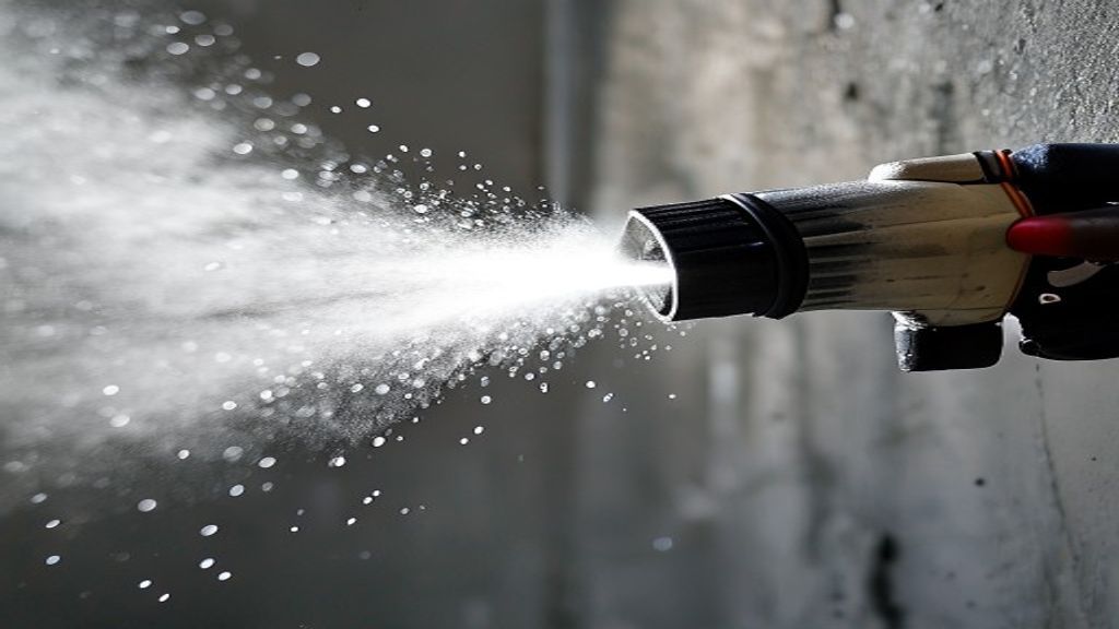 Close-up of paint sprayer nozzle spraying fine atomized paint mist